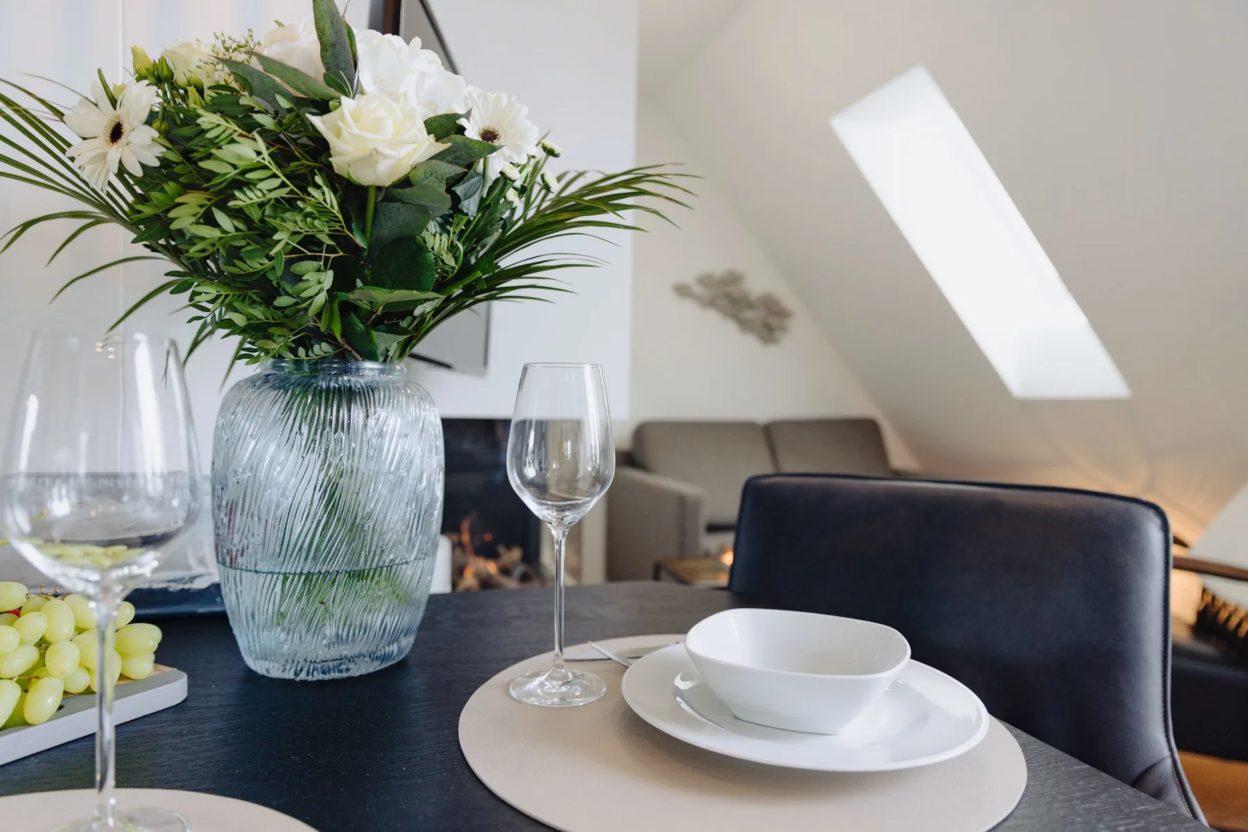Ferienwohnung Wellenbrecher Sylt – Blumenstrauß mit Weingläsern auf dem Esstisch