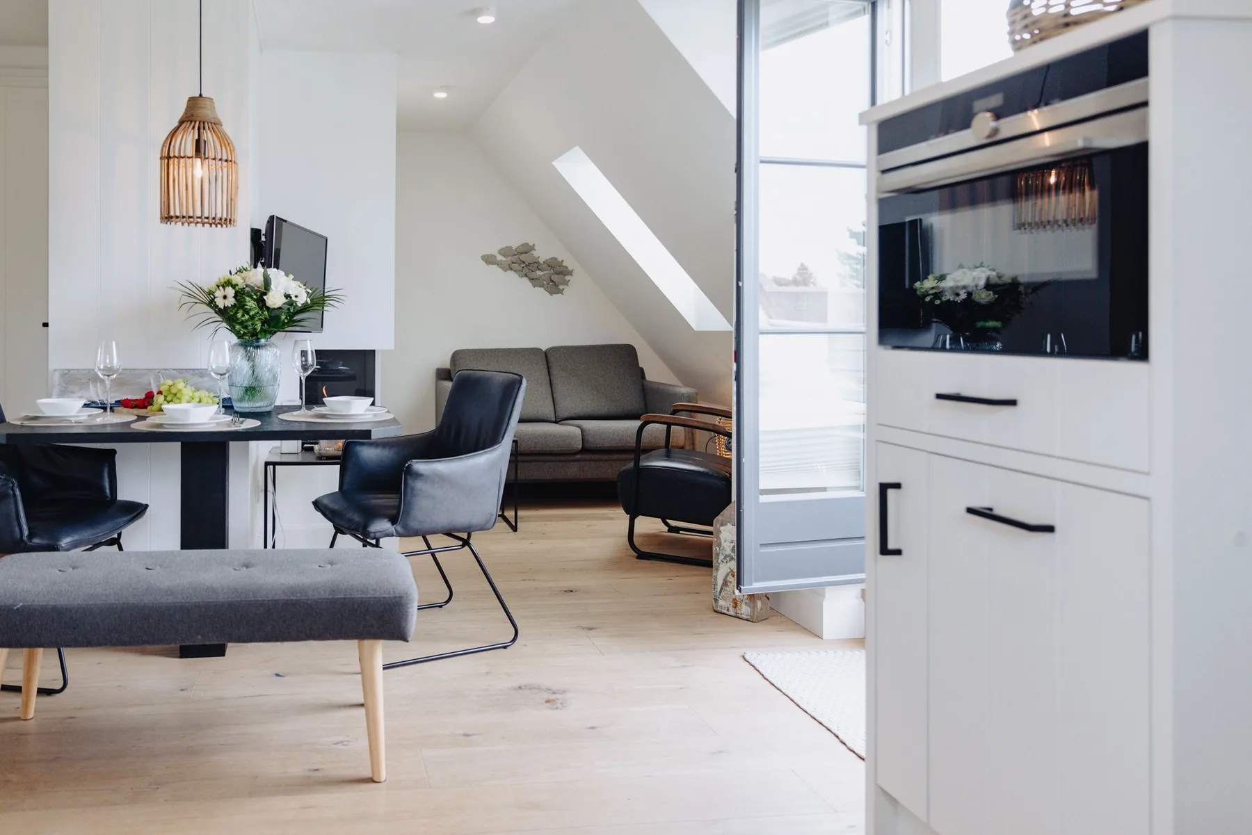 Ferienwohnung Wellenbrecher Sylt – Wohn- und Essbereich mit Rattanlampe